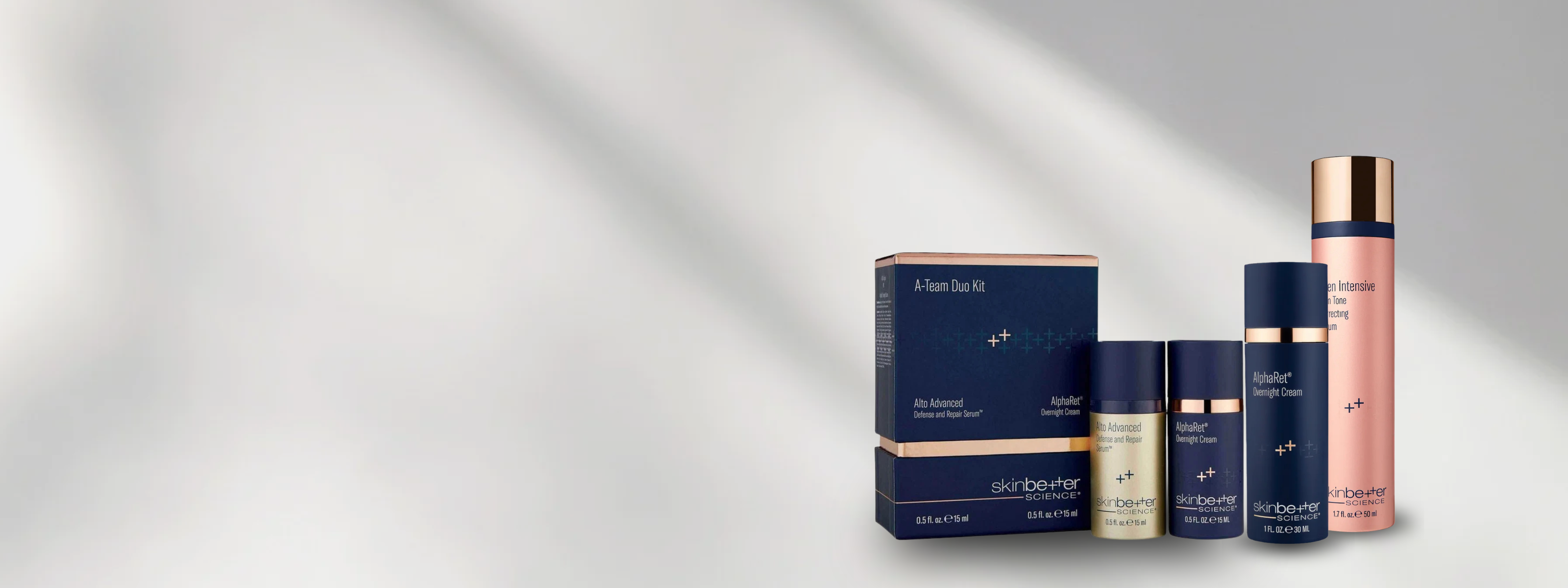 A skincare set from Aesop Beauty, including a dark blue box, a pink bottle, and two dark blue jars, arranged on a light gray background with soft diagonal shadows.